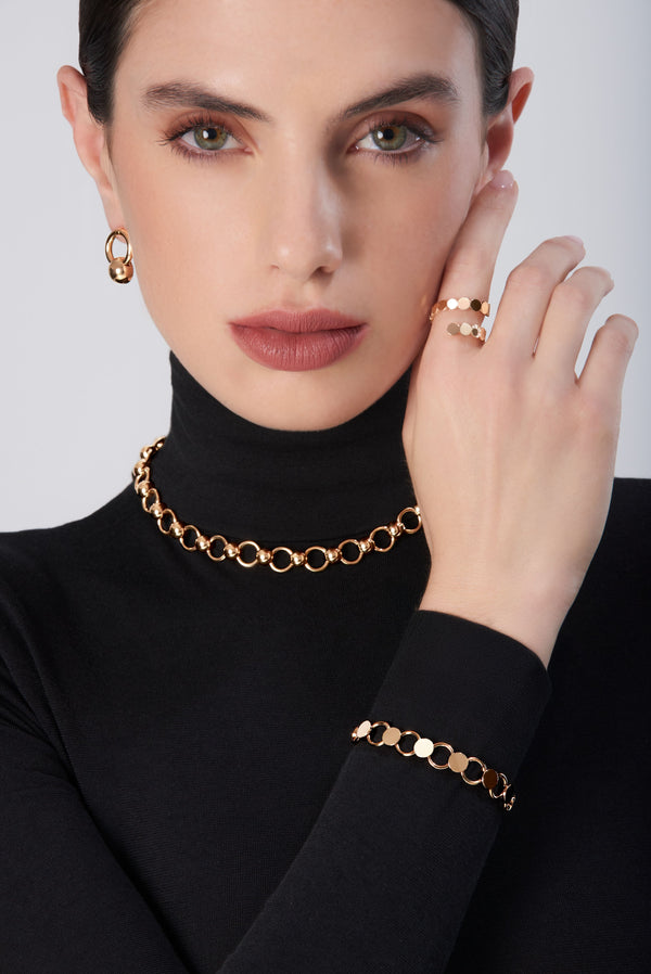 Woman wearing rose gold hoop earrings, necklace, bracelet, and ring in 18k gold with circles