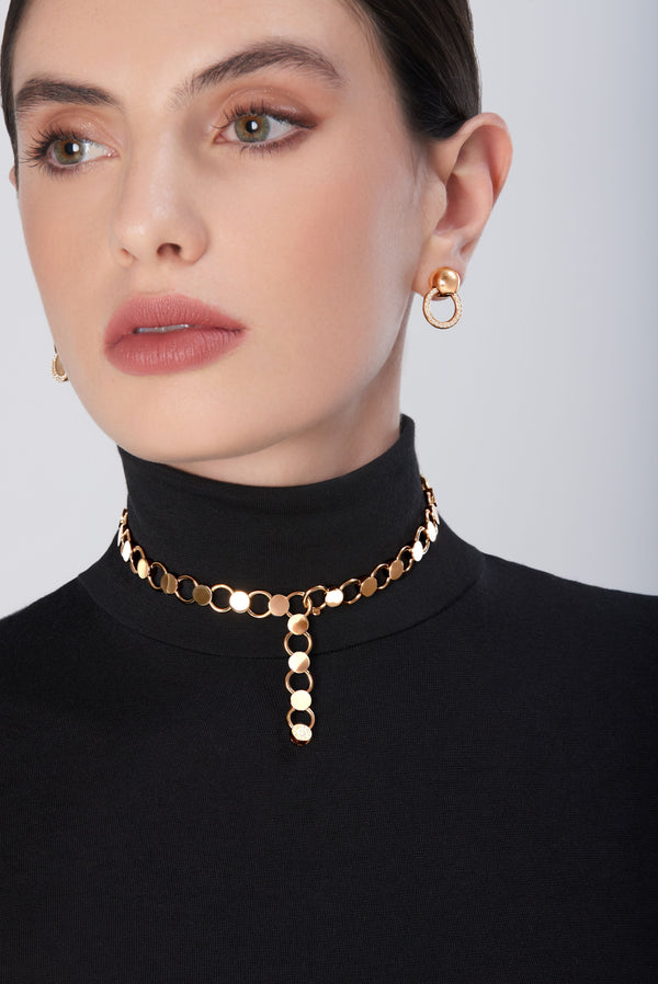 Choker in 18k gold with matching hoop earrings, worn by model in black turtleneck sweater
