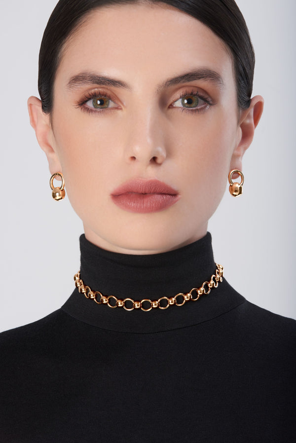 Earrings and choker in 18k gold on model wearing a black turtleneck