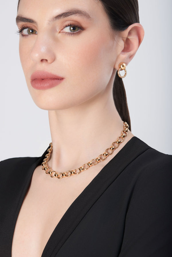 Necklace in 18k gold complementing diamond earrings, worn with a black v-neck outfit