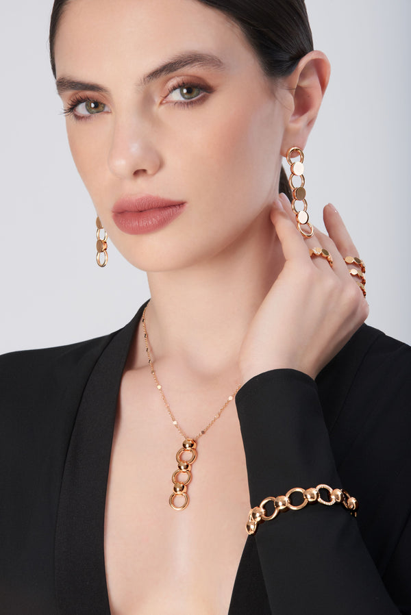Necklace, earrings, ring, and bracelet in 18k gold with link design modeled with a black jacket