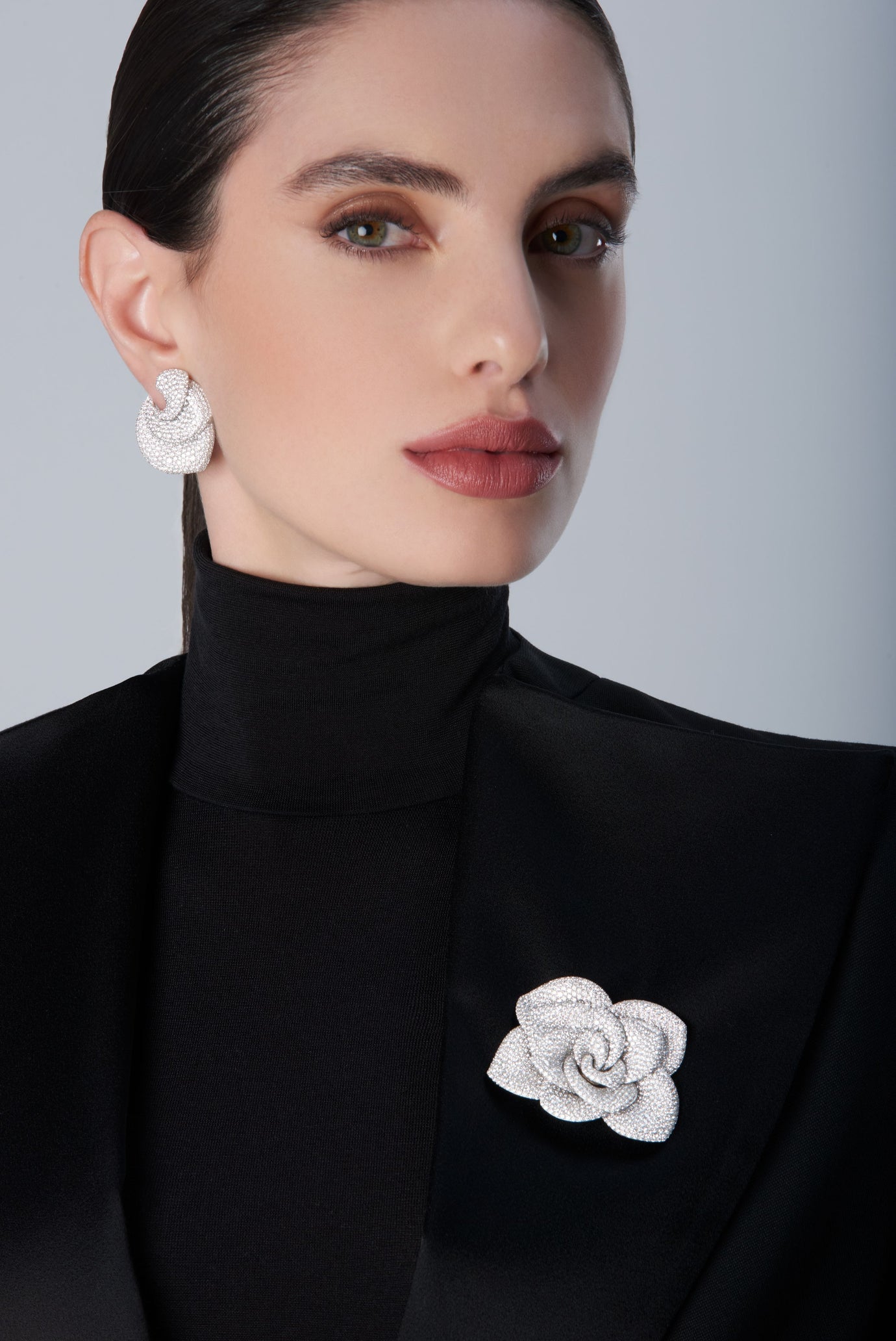Woman wearing a black turtleneck with a 18k white gold brooch and matching earrings 