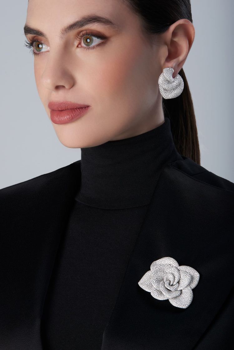 Woman wearing a black turtleneck with a 18k white gold brooch and matching earrings 
