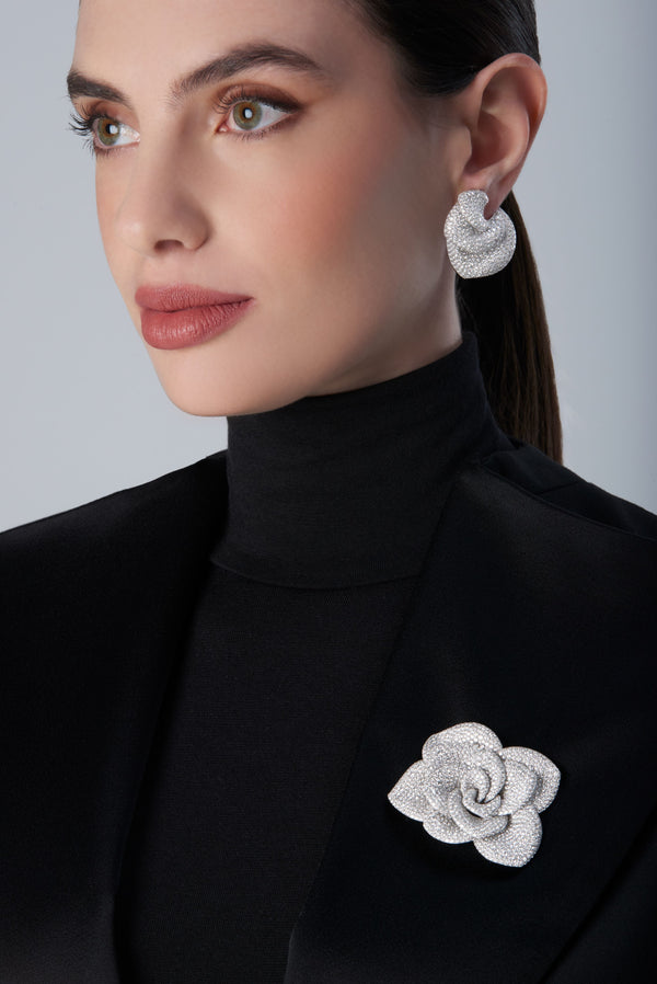 Woman wearing a black turtleneck with a 18k white gold brooch and matching earrings 