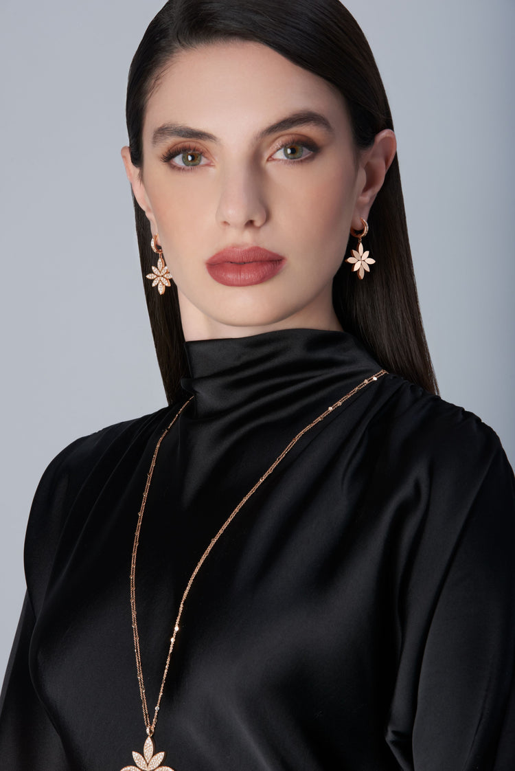 Woman wearing a black outfit with gold earrings and necklace