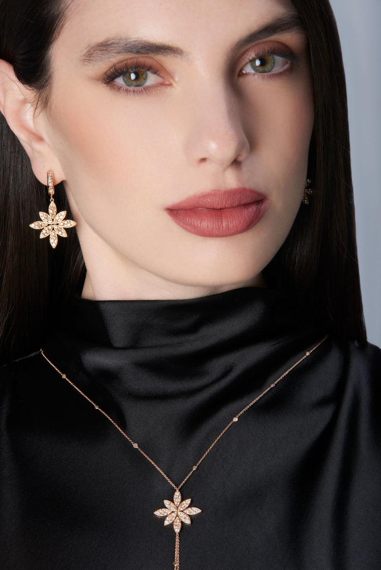 Woman wearing a black outfit with gold earrings and necklace