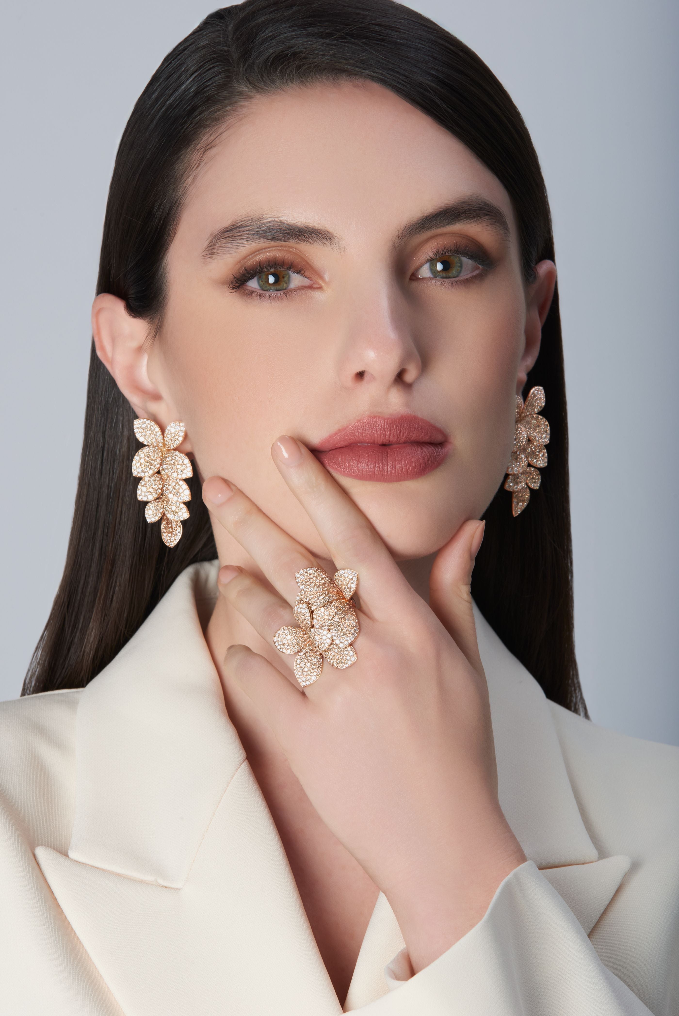 Model wearing a white jacket with Ring and earrings in 18k Rose Gold with diamonds.