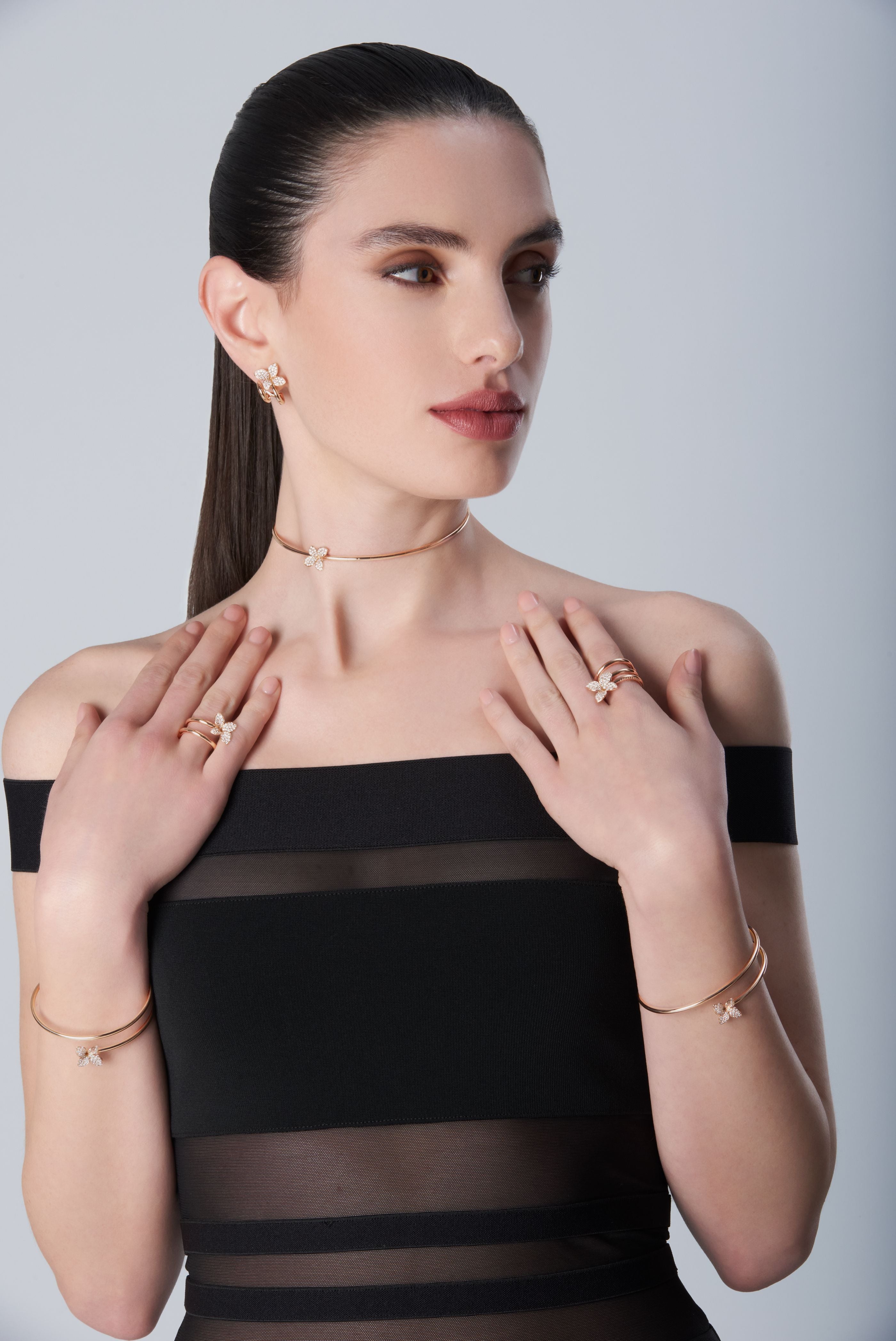 Composition of choker, rings, bracelet and earrings in 18k Rose Gold with Diamonds on model with black dress