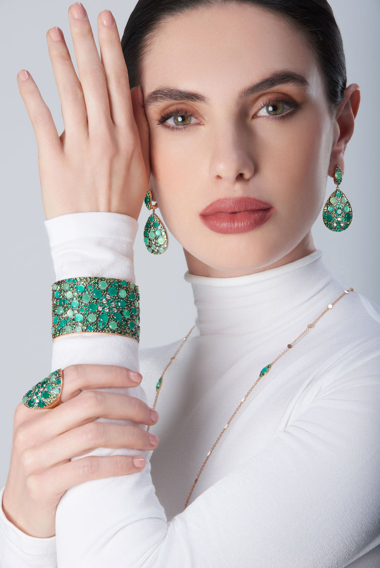 Bracelet, earrings and ring in in 18k Rose Gold with green precious gemstones on model with a white look