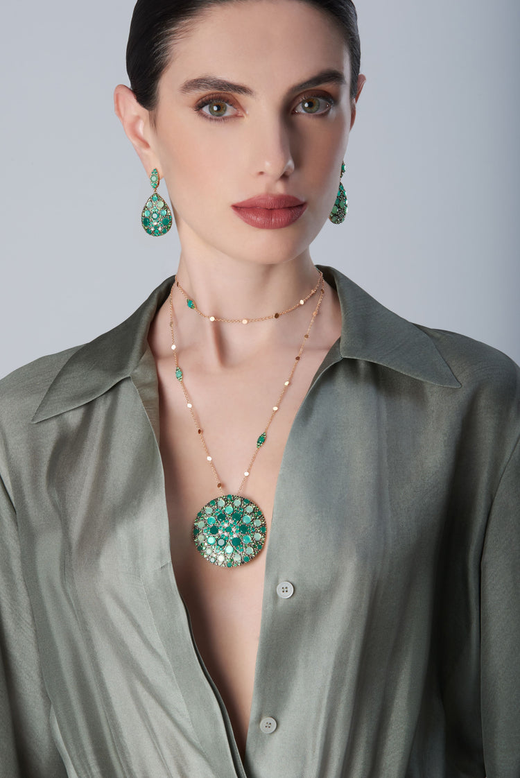 Earrings and necklace with diamonds and green gemstones on model with a green dress