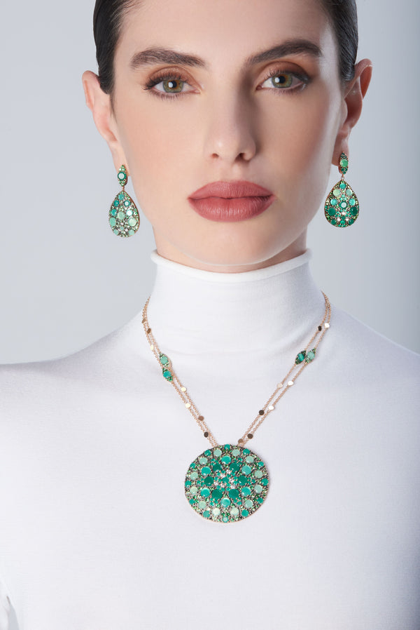Earrings and necklace in in 18k Rose Gold with green precious gemstones on model with a white turtleneck
