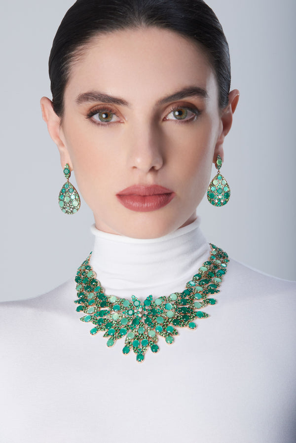 Combination of earrings and collier in 18k Rose Gold with green precious gemstones on model with a white turtleneck
