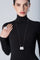 Woman wearing a black turtleneck with 18k white gold set of earrings, necklace and ring