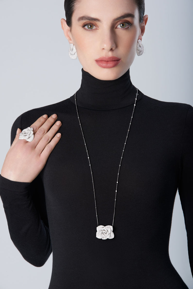 Woman wearing a black turtleneck with 18k white gold set of earrings, necklace and ring