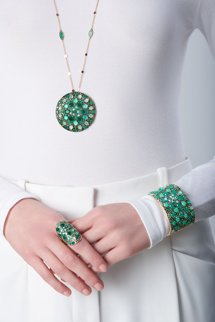 Ring, bracelet in in 18k Rose Gold with green precious gemstones on model with a white look