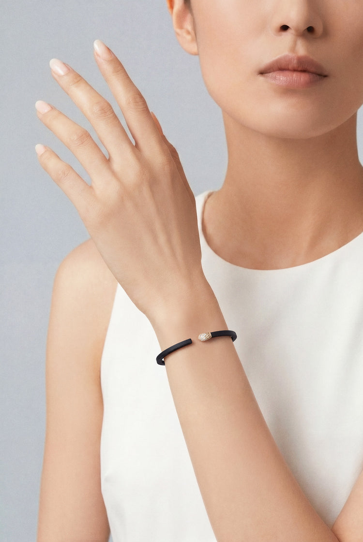 Model with a white top wearing a Bracelet in 18k Rose Gold and Black titanium with white and champagne diamonds