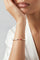 Model wearing a white top and a Bracelet in 18k rose gold with rubies