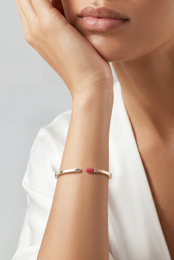 Model wearing a white top and a Bracelet in 18k rose gold with rubies