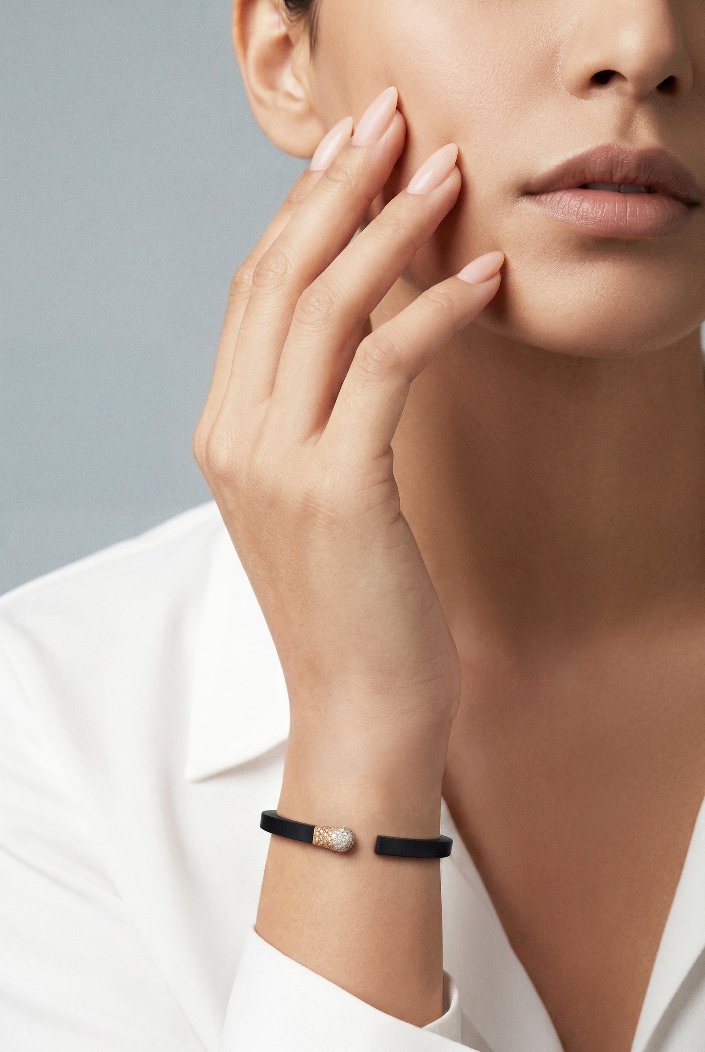 Model wearing a white shirt and a Bracelet in 18k rose gold and black titanium with white and champagne diamonds