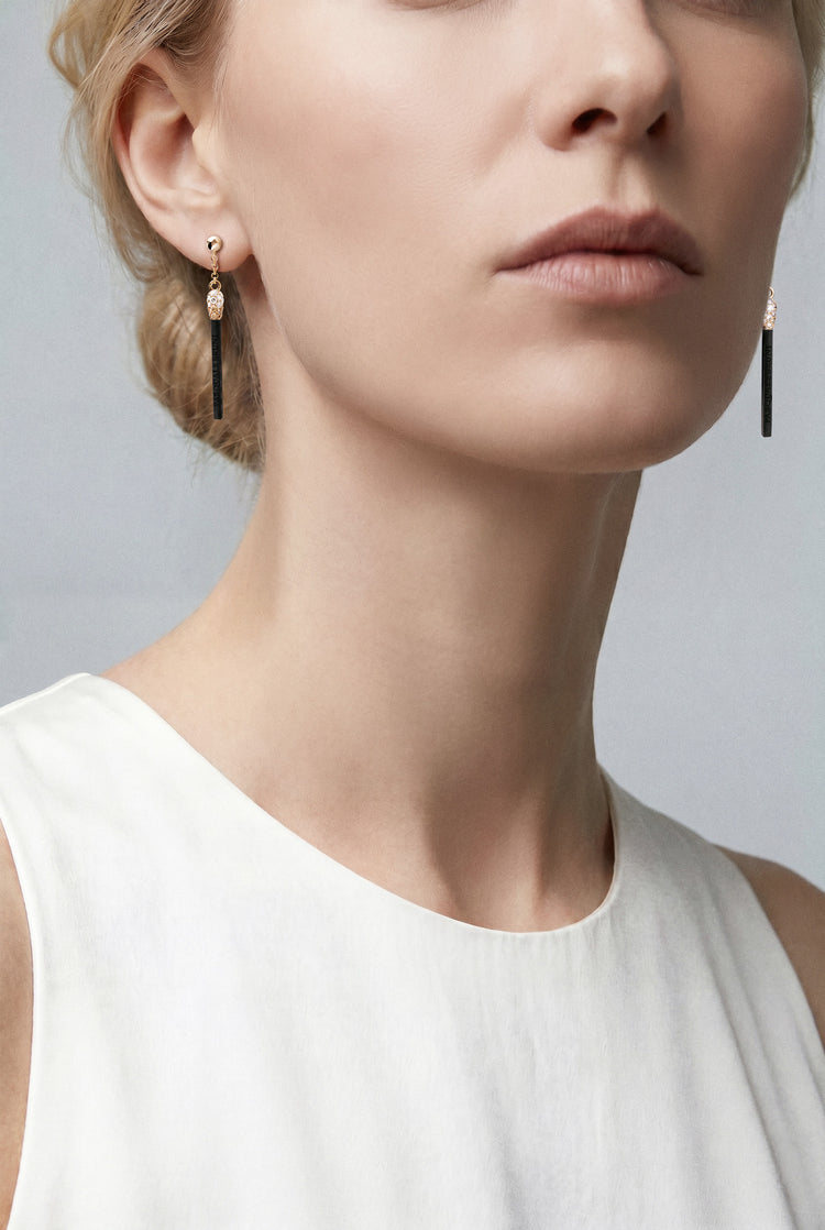 Model wearing a white top and Earrings in 18k Rose Gold and Black Titanium with White and Champagne Diamonds.